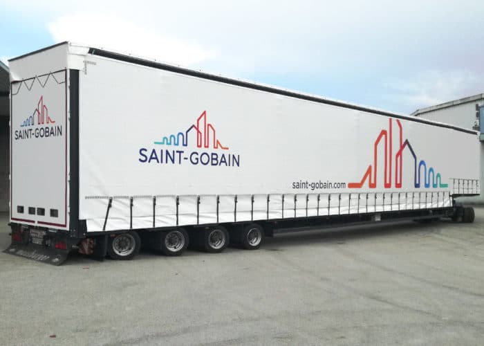 Das Bild zeigt einen über 20 Meter langen Meusburger-Auflieger der Firma Saint Gobain. Mit diesem Transporter ist das Unternehmen in der Lage, große Mengen an Gütern sicher und zuverlässig zu transportieren.